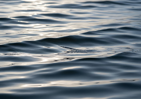 A detailed abstract shot of calm water, showing gentle waves and light reflections across its surface.の素材