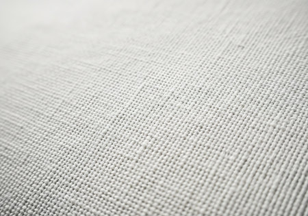 A close-up view of a light-colored textured surface with a subtle crisscross pattern and a gentle sheen.の素材