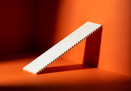 A stark, minimalist scene featuring a white saw blade casting a sharp shadow against a vibrant orange backdrop.の素材