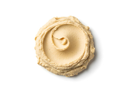 A dollop of smooth, beige hummus artfully swirled, presented on a clean white surface.の素材