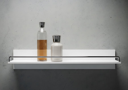 A minimalist white shelf mounted on a textured wall displays two decorative bottles, one amber and one white.の素材