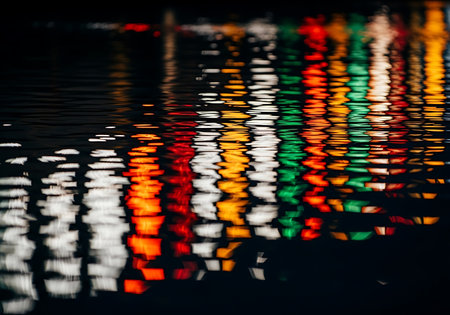 Abstract pattern of colorful city lights distorted by the gentle movement of water, creating a mesmerizing visual effect.の素材