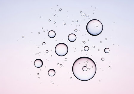 Clear water droplets of various sizes scattered across a soft, gradient background, creating a delicate and refreshing visual.の素材