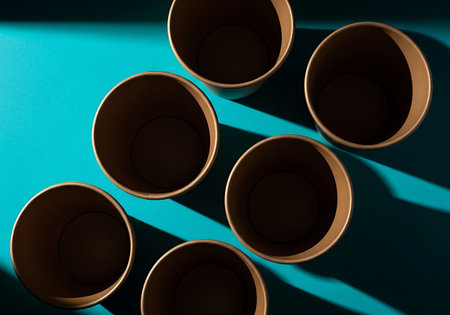 Several round wooden coasters are artfully arranged on a vibrant teal surface, casting distinct shadows.の素材