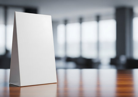 A clean white table tent stands on a polished wooden table, ready for custom branding or information.の素材