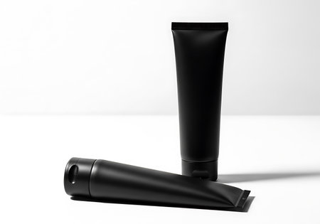 Two sleek black tubes, one standing upright and the other lying down, are presented against a clean white backdrop.の素材