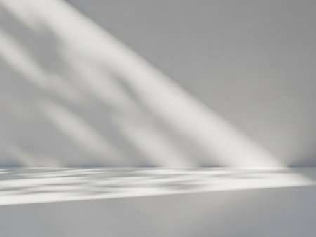 A clean, minimalist scene featuring diagonal light beams and dappled shadow patterns cast across a smooth gray background and floor.の素材