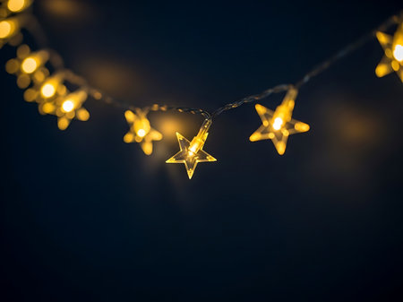 A string of luminous golden star-shaped lights glows against a deep, dark backdrop, creating a magical atmosphere.の素材