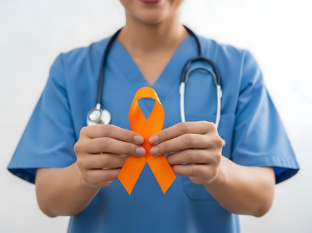 A healthcare professional wearing blue scrubs and a stethoscope holds an orange ribbon, symbolizing awareness and support for leukemia. The image conveys a sense of care and advocacy for those affected by the disease.の素材