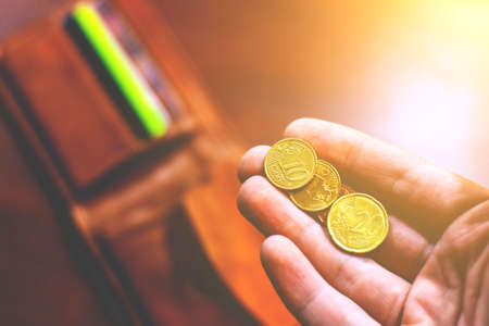 Coins in hand with wallet in the backgroundの写真素材