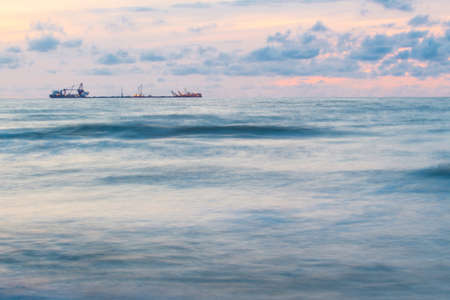 Beautiful sunset over the sea and ship on the horizon
