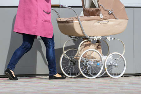 a woman is walking with a baby in a strollerの写真素材