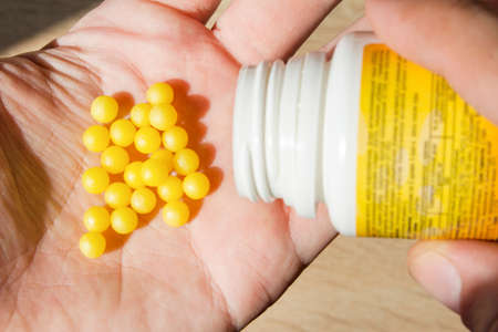 yellow round vitamins in hand