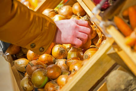 a man chooses an onion in a storeの写真素材