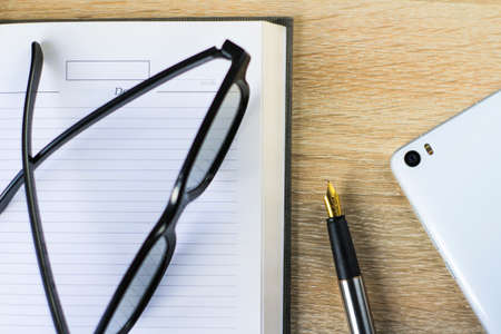 fountain pen and glasses lie on a notebookの写真素材