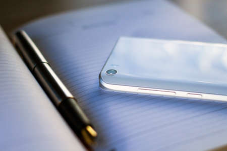 fountain pen, smartphone and glasses lie on a notebook