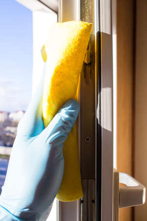 The hand in the rubber glove wipes the window with a yellow cloth