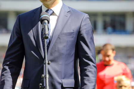 a man in a suit stands in front of a microphoneの写真素材