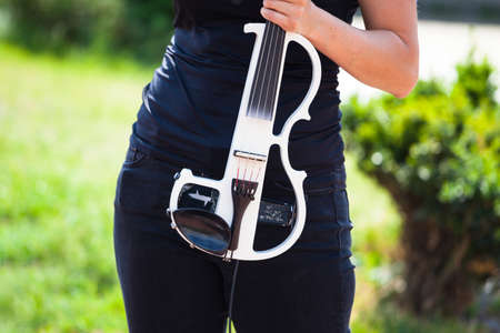 white electric violin in the hand of a young girlの写真素材