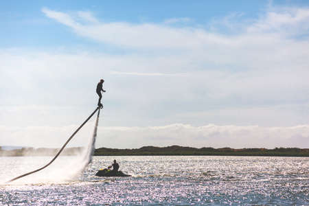 a man is riding a flyboard on a lake on a sunny day, toned