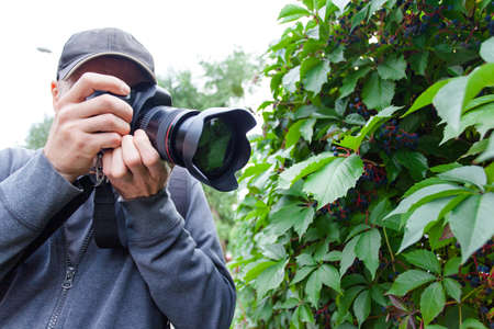 male photographer with a large professional camera looks into the viewfinder and takes pictures of a...