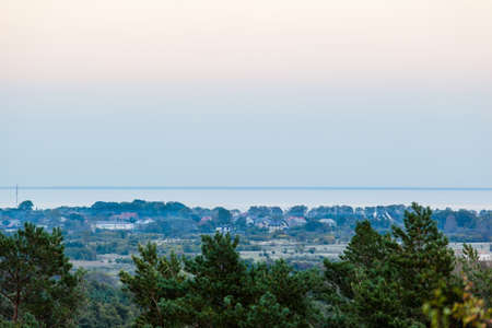 twilight during the blue hour over the forest and a small village by the sea