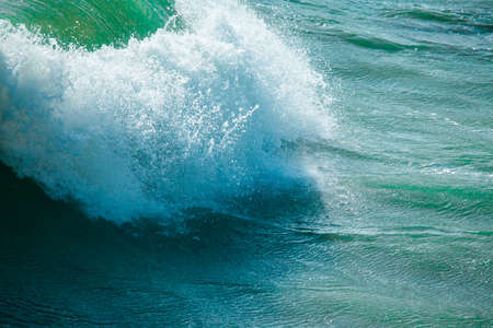 surface of turquoise ocean water with waves, spray and white foamの写真素材