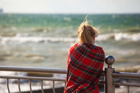 girl wrapped in a plaid on the beachの写真素材