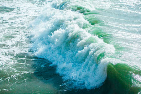 surface of turquoise ocean water with waves, spray and white foam