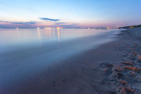 smooth sea surface and coast in purple twilight on long exposureの写真素材