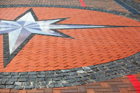 a sign of wind rose on a sidewalk tileの写真素材