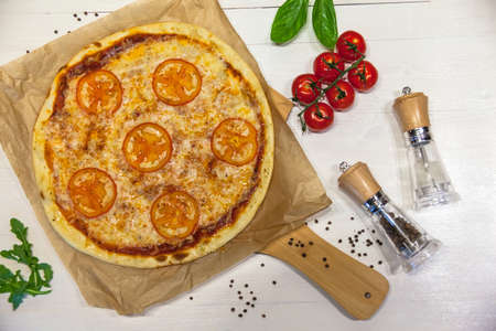 appetizing margarita pizza with spices on a white table, flat layの写真素材