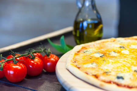 appetizing pizza from four cheeses with olive oil on a black tableの写真素材