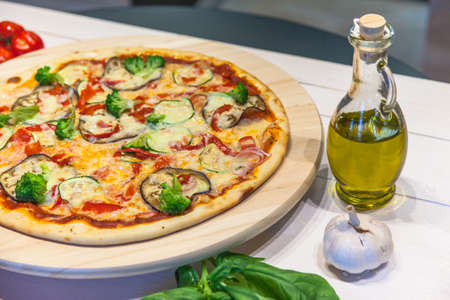 appetizing vegetarian pizza with olive oil on a white tableの写真素材