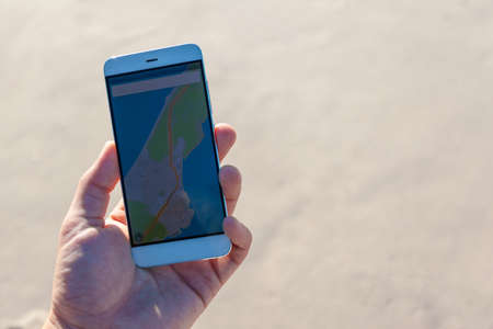 close-up of a hand with a smartphone with a navigator and terrain mapsの写真素材