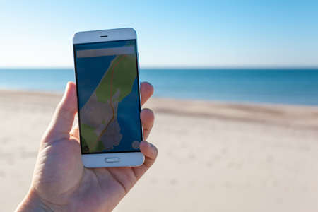 close-up of a traveler's hand with a smartphone with a navigator and terrain mapsの写真素材
