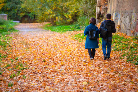 the guy and the girl are walking in a beautiful autumn park