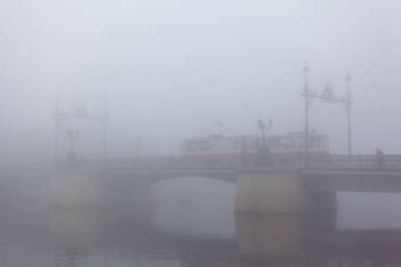 silhouette of a bridge with a tram in a thick fogの写真素材