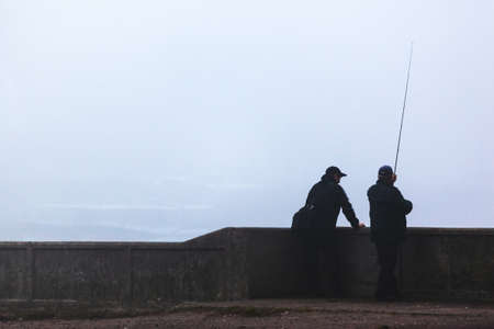 a man is fishing in a thick fog