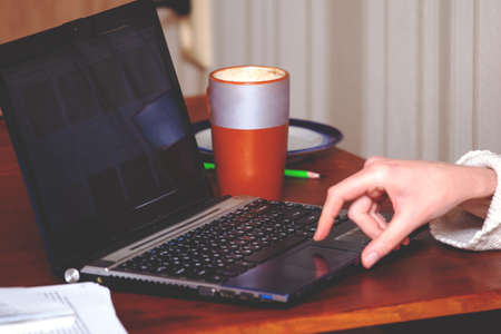 girl works at home with a laptop with a mug of coffee, retro tonedの写真素材