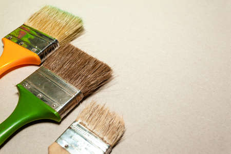 three paint brushes of different sizes lie on a smooth light surfaceの写真素材