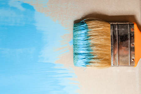 paint brush in blue paint on an unpainted flat surface, copyspaceの写真素材