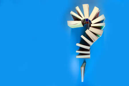 question mark from a stack of books on a blue background, concept, copy space