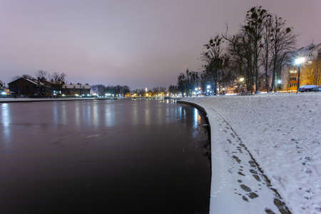 romantic night snow-covered park with lanterns and a lakeの写真素材