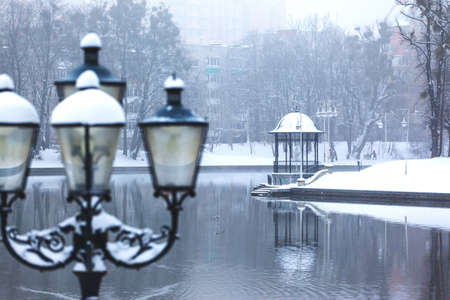 winter cityscape by the lake with a gazebo
