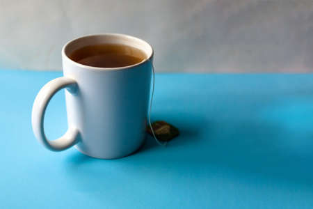 mug with tea in a bag on a blue table, copy space