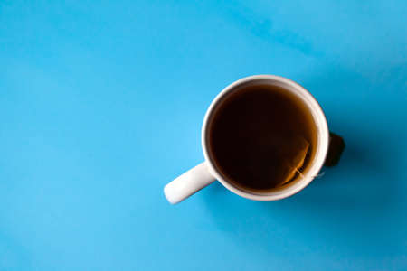 mug with tea in a bag on a blue background, copy space, flat layの写真素材
