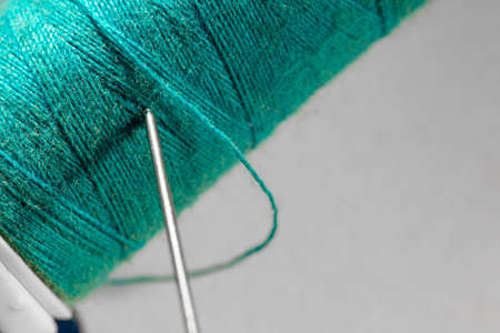 blue thread reel with needle stuck in macro