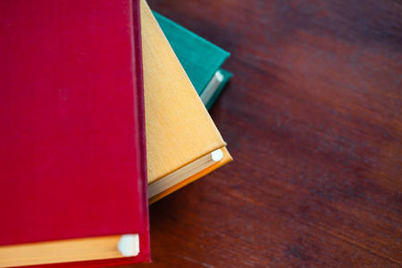 old large books with red, yellow and green covers are on a wooden table, flat lay