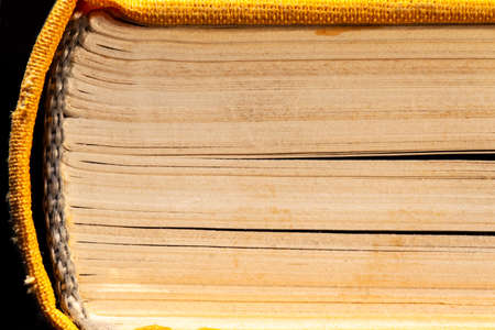 side view of the old yellow pages and spine of a thick book, macro